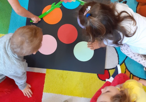 Dzieci łapką na muchy uderzają w kolorowe kropki
